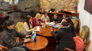 Professor Michaela DuBay collaborating with Bolivian community members to enhance autism care, sitting together in a meeting room setting with educational materials on the table