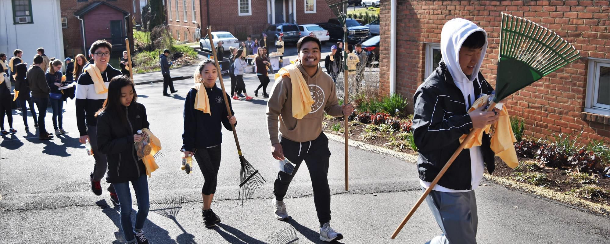 banner image 4 students walking with rakes