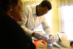 Randy Jones at Fifeville clinic with patient doing blood glucose test