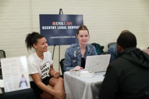 Photo taken at Decarceration Clinic event; two Law students sit across the table from an event goer