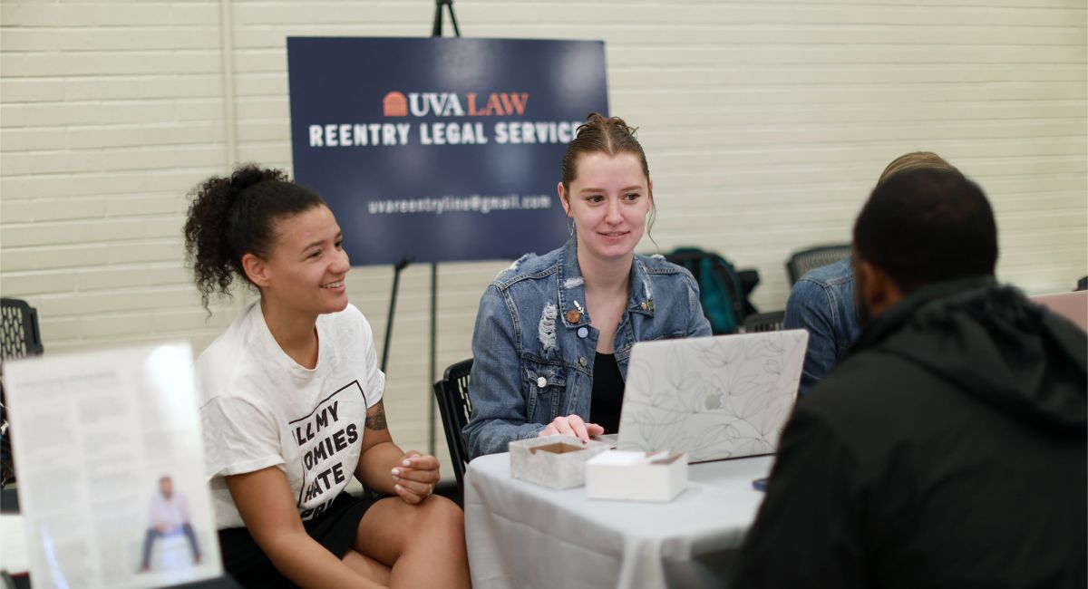 Photo taken at Decarceration Clinic event; two Law students sit across the table from an event goer